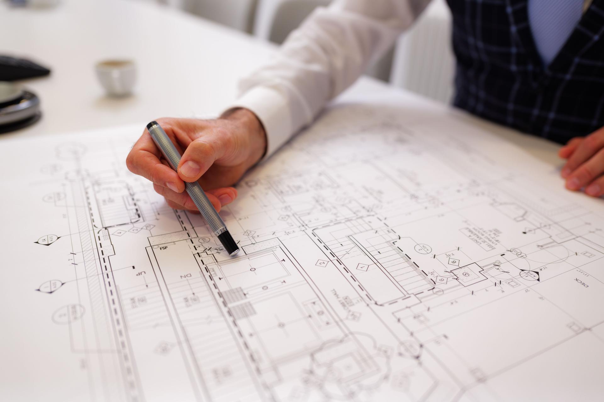 Architect reviewing blueprint on a white table with pen in hand